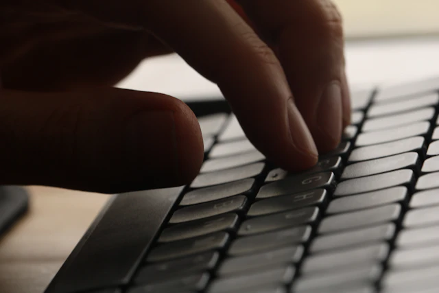 Une main tape une recherche sur le clavier d'un ordinateur portable