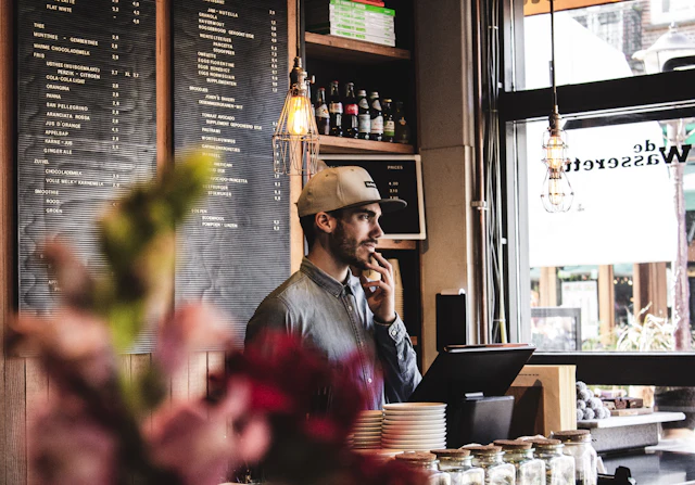 Un commerçant au comptoir de son café, au téléphone